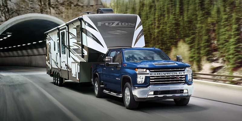 A blue 2023 Chevy Silverado 2500 towing a trailer.
