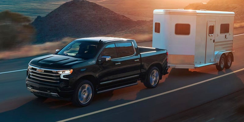 A photo of a 2024 Chevy Silverado 1500 towing a horse trailer.