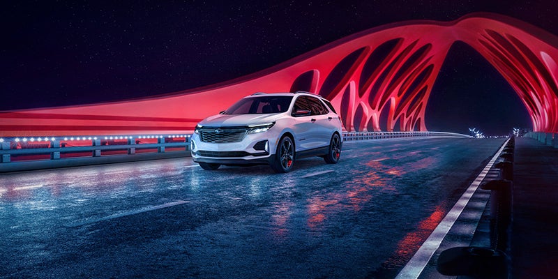 A photo of a 2024 Chevy Equinox driving on a bridge at night
