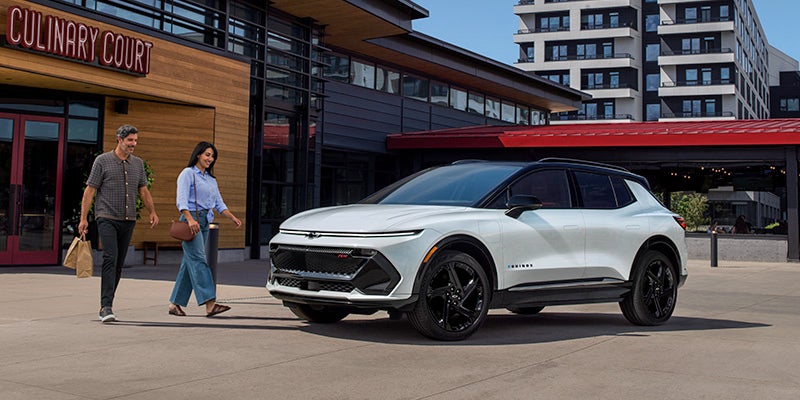 A photo of two people walking to a 2024 Chevy Equinox EV