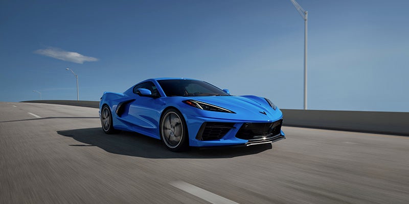 A blue 2024 Chevy Corvette Stingray speeding down a highway